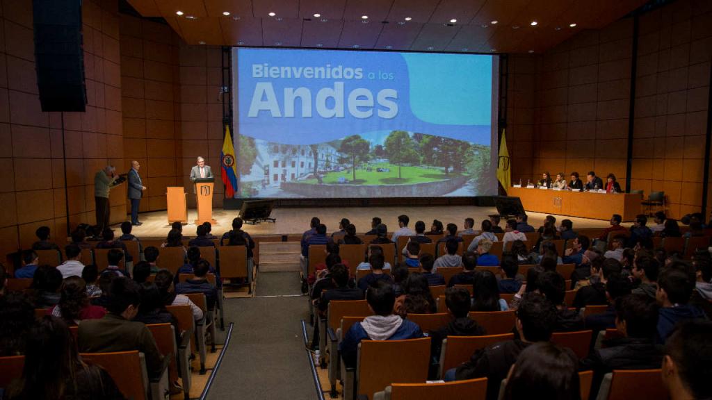 Auditorio lleno de estudiantes viendo una pantalla que dice: Bienvenidos a Los Andes. 