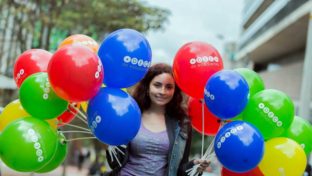 Una señorita con globos de colores inflados en las manos