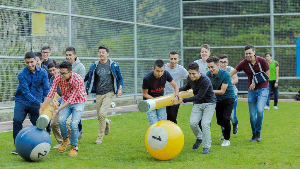 Jóvenes jugando en el cesped con bolas de billar gigantes. 