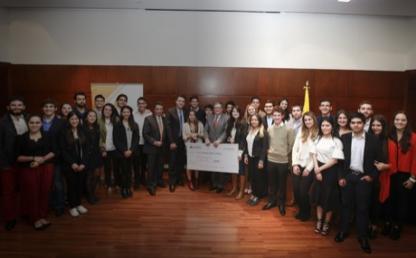 Grupo de egresados y el rector de la Universidad de los andes posan para al foto sosteniendo un cheque gigante