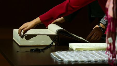 Primer plano de una mano que firma un libro. 