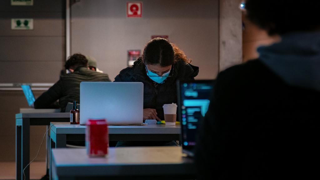 Estudiantes con tapabocas y computadores. 
