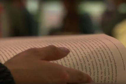 Primer plano de una persona leyendo un libro en el estand de Uniandes en la Feria Internacional del Libro de Bogotá