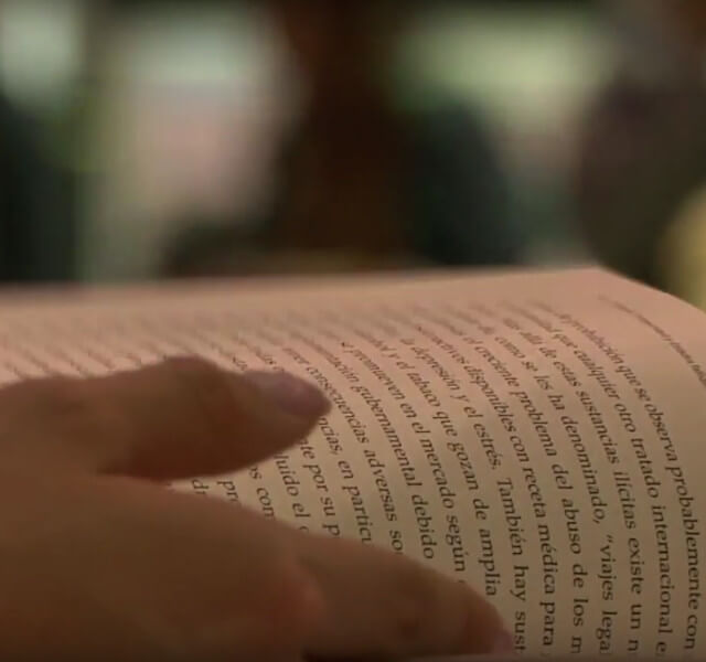 Primer plano de una persona leyendo un libro en el estand de Uniandes en la Feria Internacional del Libro de Bogotá