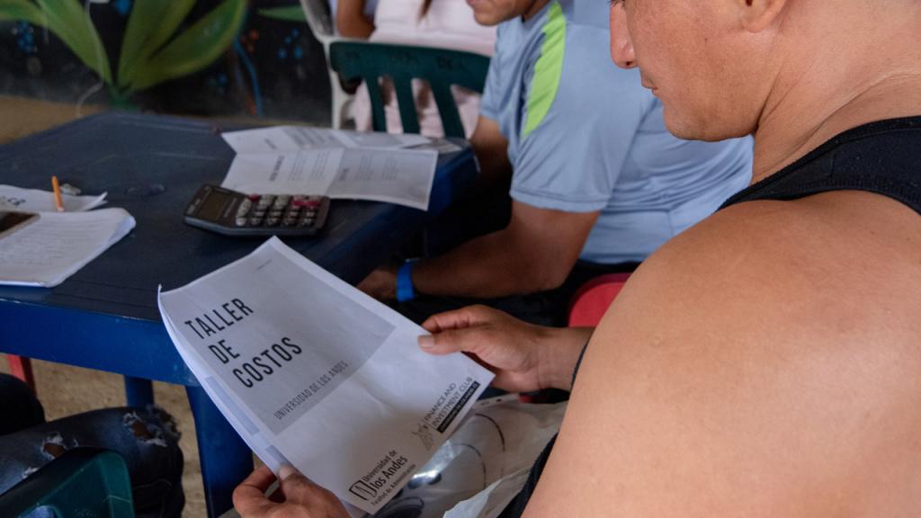 Manos sostienen una hojas tituladas Taller de costos