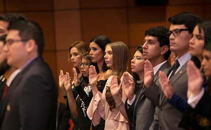 Estudiantes con la mano elevada para toma de juramento