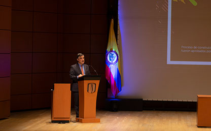 Foto en plano general de Carl Langebaek, vicerrector académico de Uniandes en atril ofreciendo discurso.