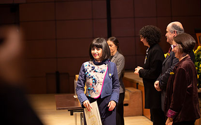Mujer camina frente a mesa de entrega de diplomas