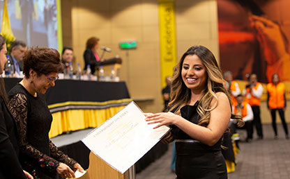 Joven mujer portando su diploma de grado de Uniandes