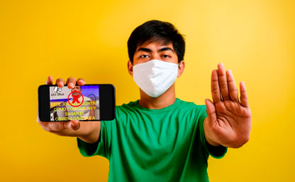 Foto de persona con tapabocas y un celular con una ilustración de COVID-19