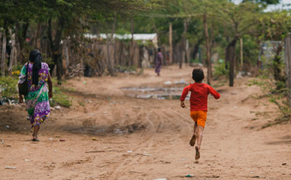 Mujer y niño indígena wayú caminando por una calle destapada en la Guajira. 