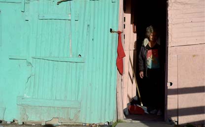 Mujer se asoma por la puerta de una casa.