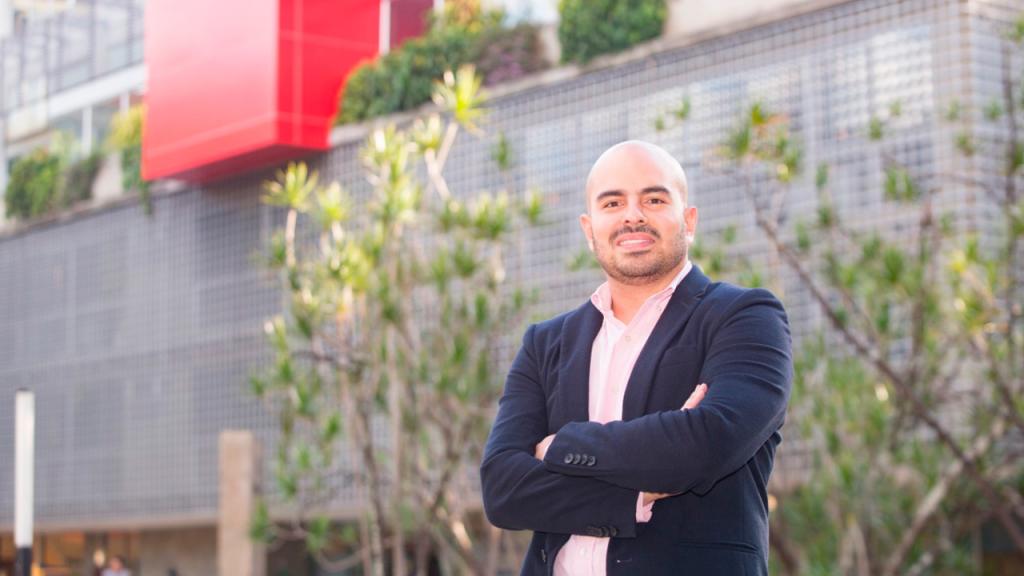 Santiago Tobón frente a un edificio Gris con muro rojo
