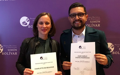 Dos personas, ganadoras del Premio Simón Bolívar, posan con un diploma 