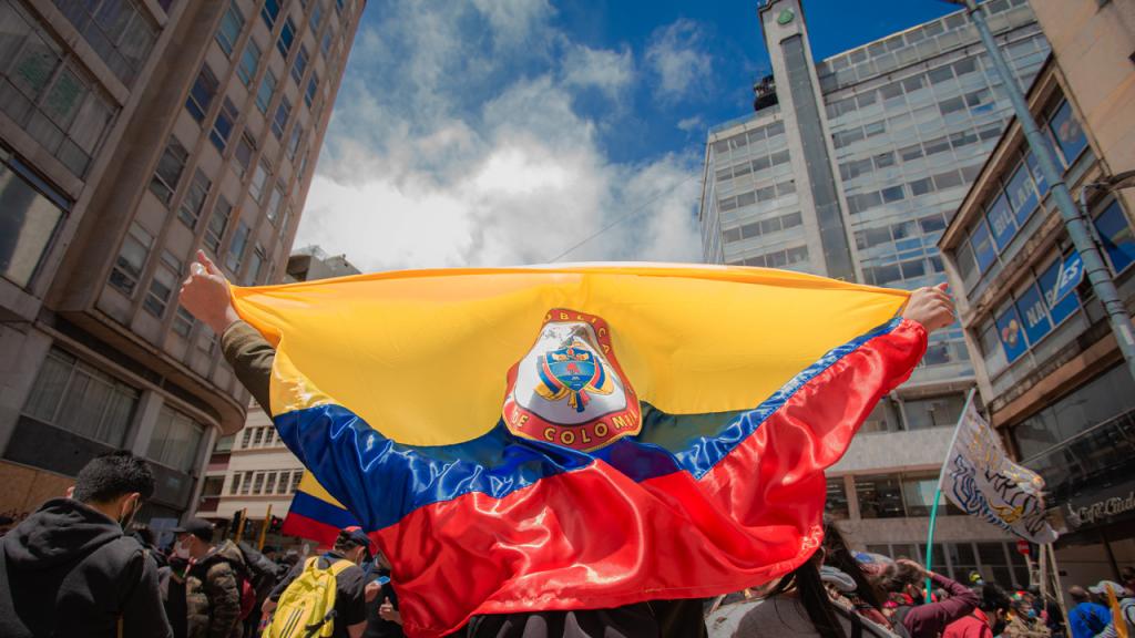 Un manifestante se arropa con la bandera de Colombia.