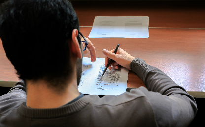 Un joven estudiante escribendo sobre un papel. 