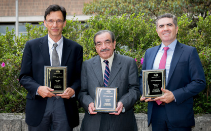 Tres profesores de la Universidad de los Andes exponen placa de reconocimiento. 