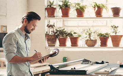 Emprendedor tomando nota en su taller decorado con plantas