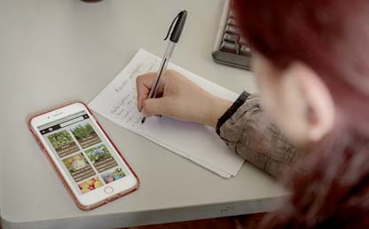 Mujer escribiendo sobre un escritorio al lado de un smartphone