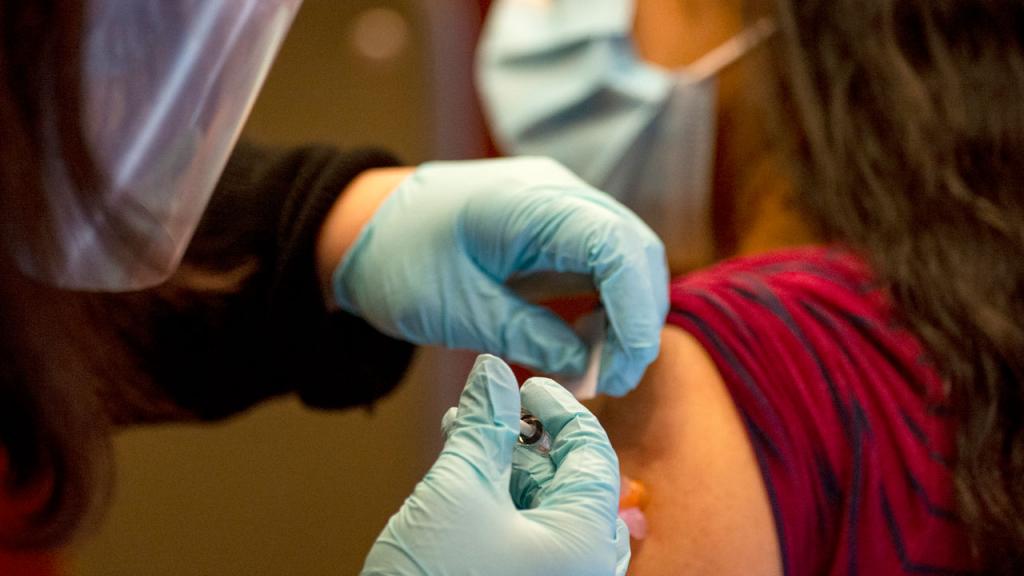 Foto de personal médico aplicando una vacuna a una mujer